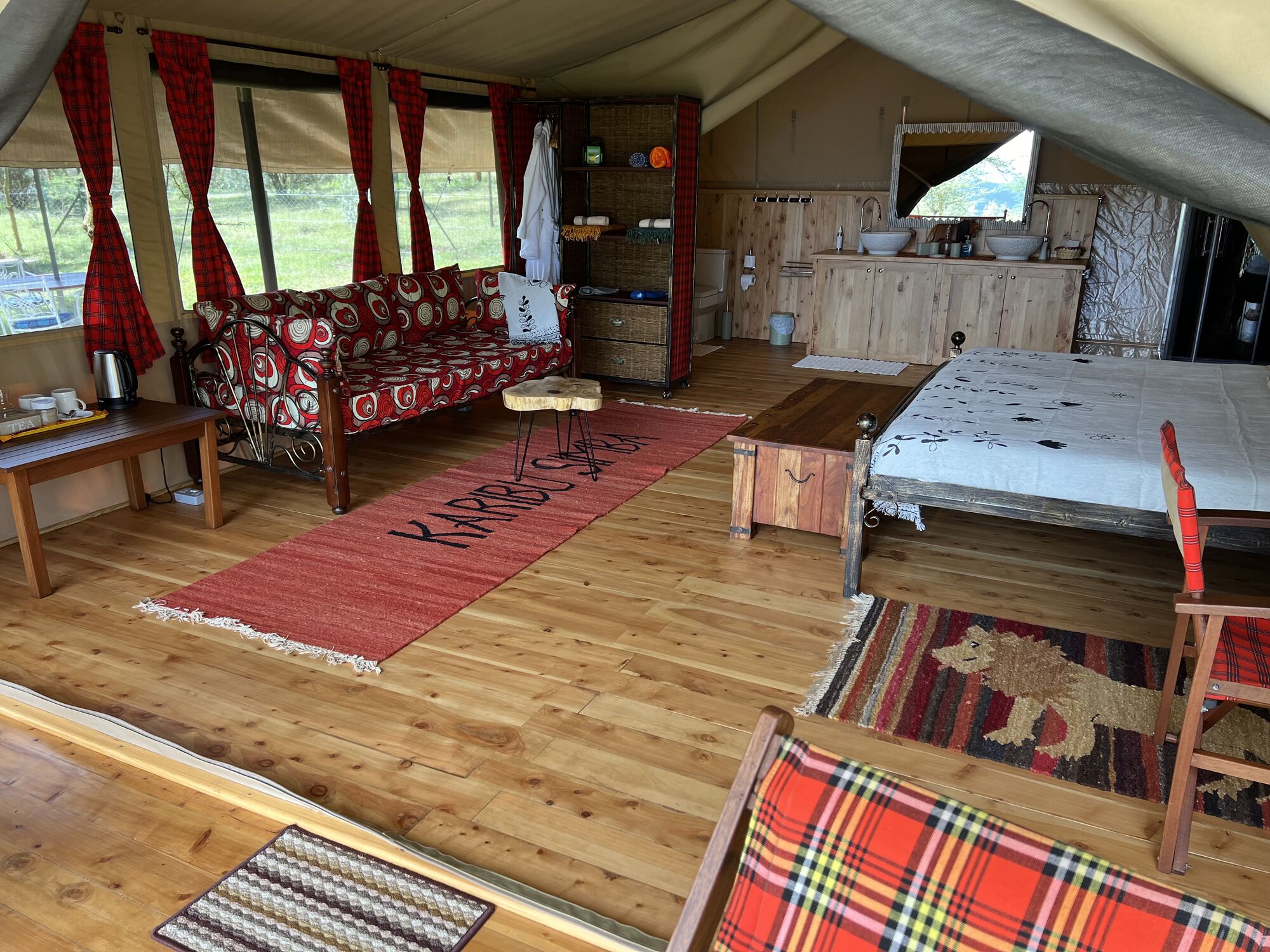 Bedroom area of a safari tent with sofa, rugs and a double bed